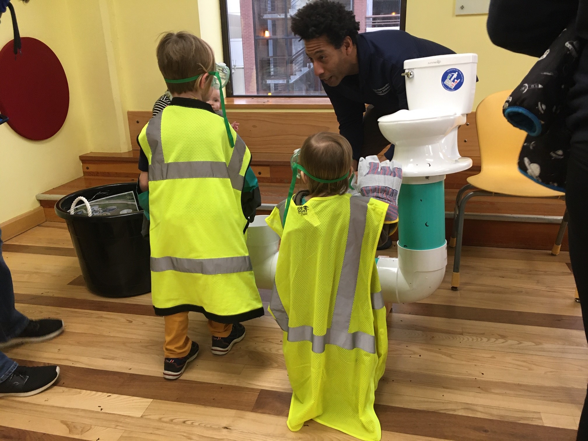 A Madison Metropolitan staff member educating 2 small children on where sewerage goes once it is flushed.