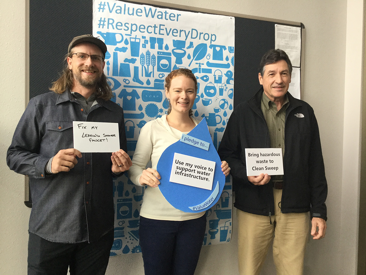 Three visitors holding signs explaining how they value water.