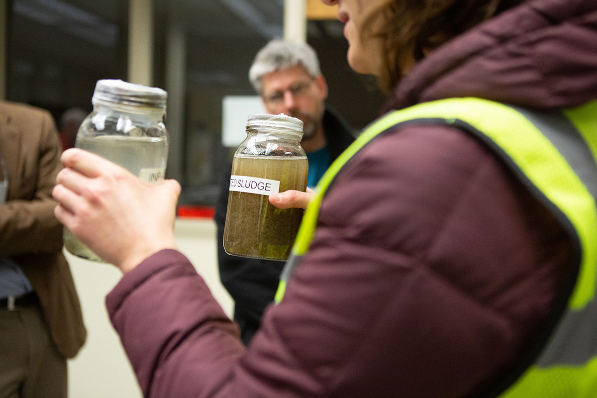 A District staff member showing a tour guide the difference between wastewater when is comes into the plant and when it leaves the plant.